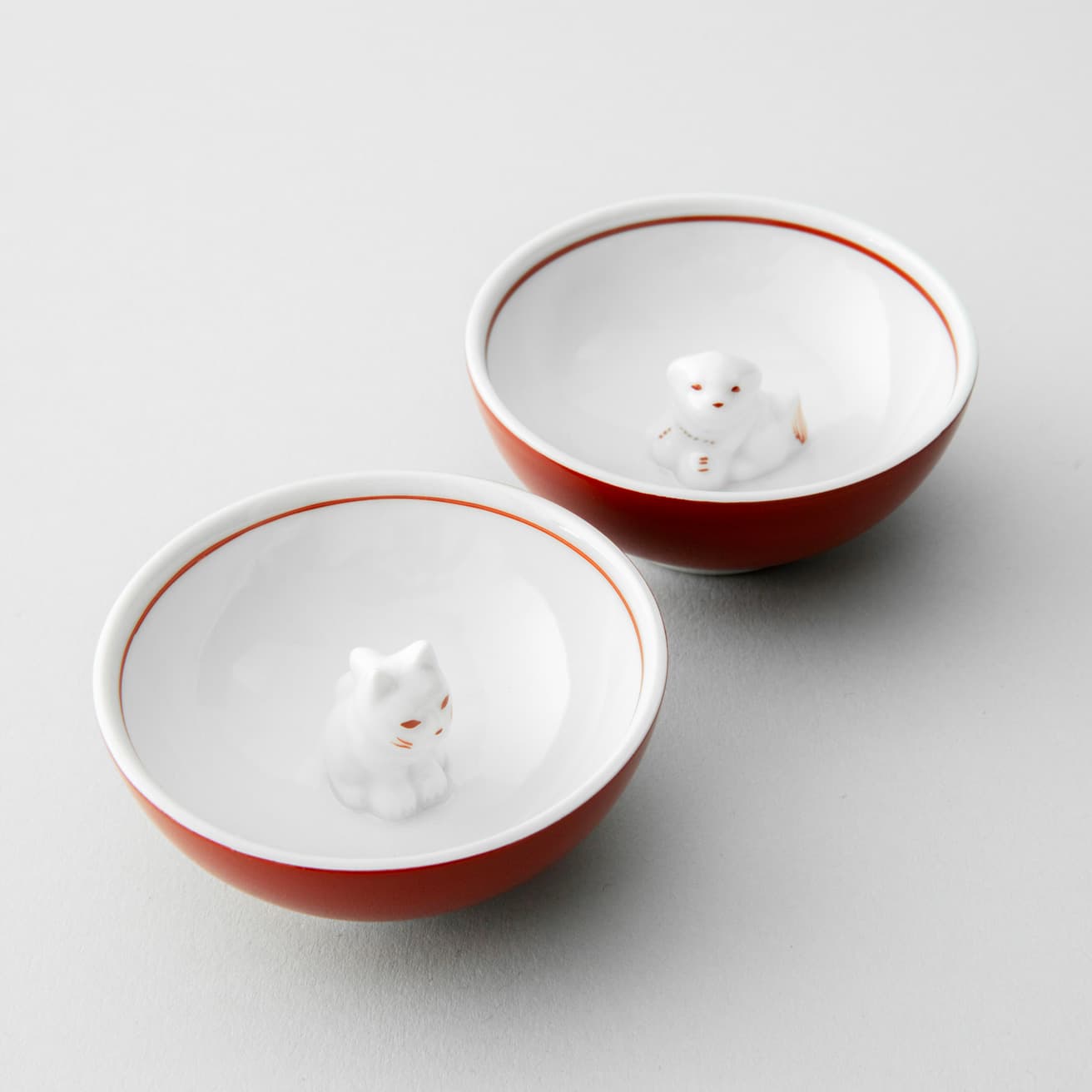 《猫盃 赤》、《犬盃 赤》各4,950円。角度によって笑顔にも見える。これで晩酌をすれば、1日の疲れも癒やされる。絵付けはすべて手作業。電子レンジに対応。
