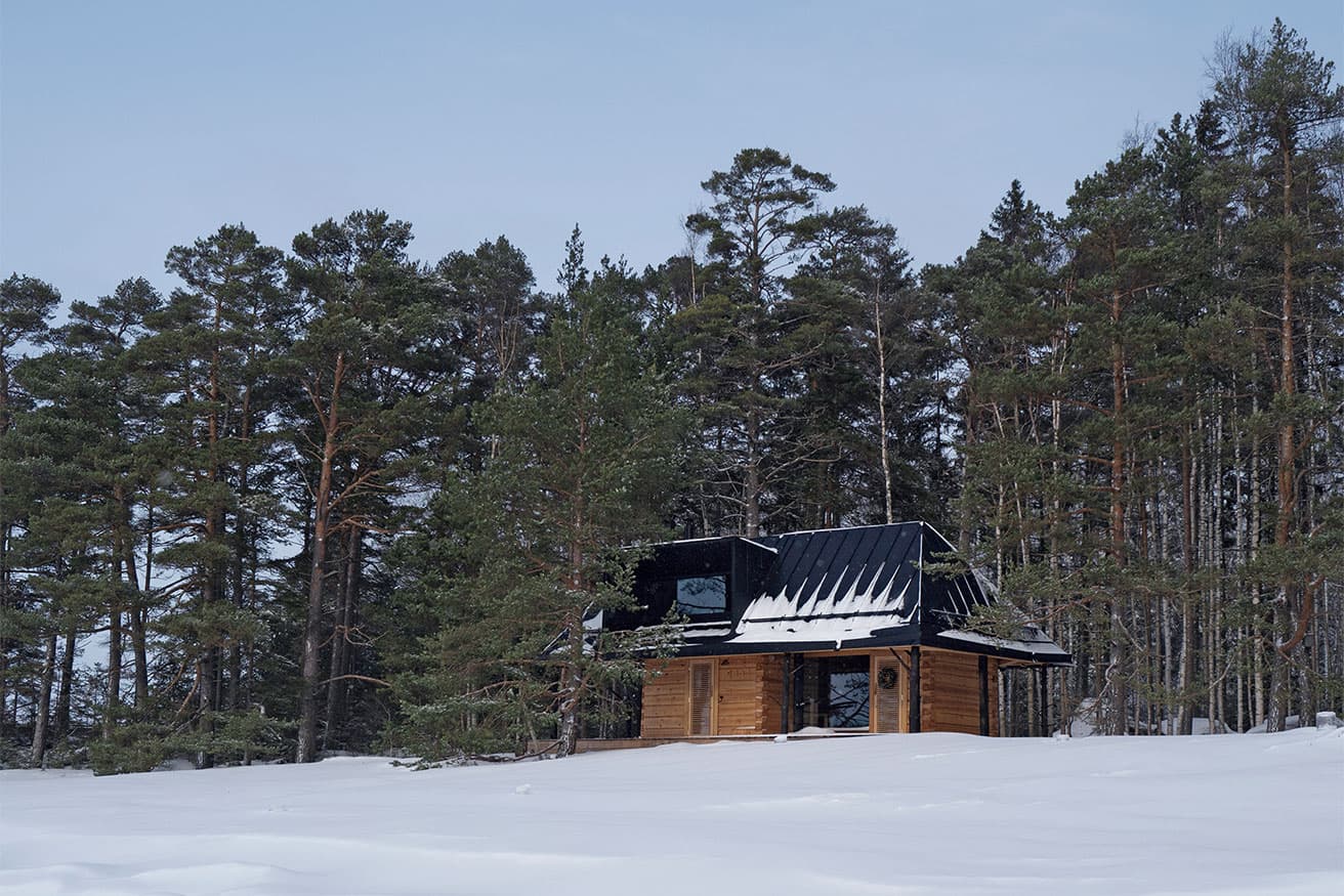 前方は海、後方は森という絶好の立地に建つ 〈Puusauna〉が雪に包まれた冬の姿。