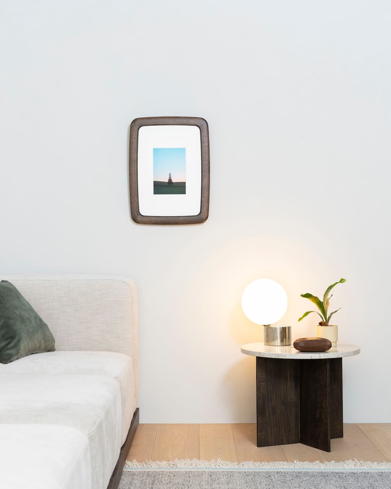 空間の中で柔らかな存在感をたたえる《frame ROUND by karimoku》。サイドテーブル《N-ST01 Side Table(Small)》249,700円（カリモク家具 TEL 0562 83 1111）、クッションカバー《BRUSHED》5,280円、テーブル上のボックス ZANAT《GENKANボックス》127,600円（アクタス青山店 TEL 03 5771 3591）、マイケル・アナスタシアデス《TIP OF THE TONGUE》テーブルライト430,100円（YAMAGIWA東京ショールーム TEL 03 6741 5800）。