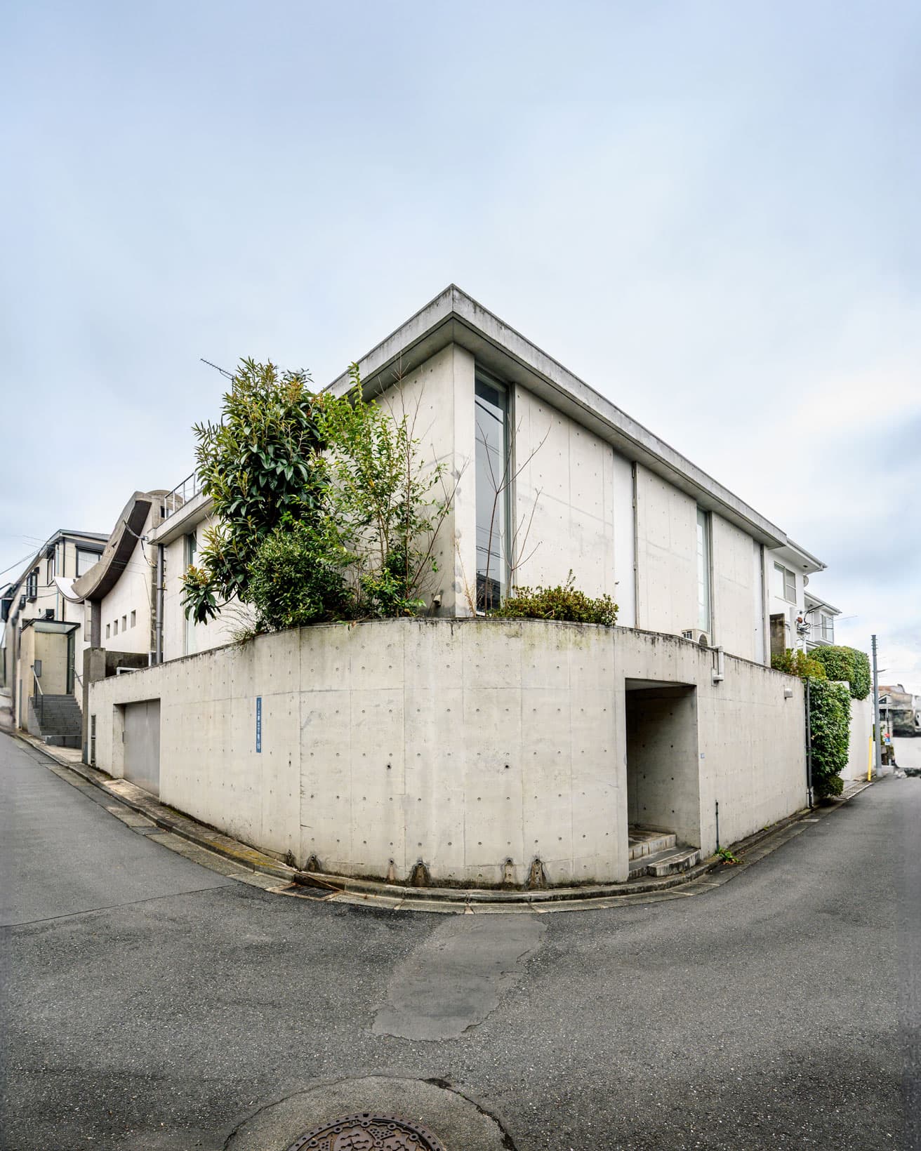 敷地北側の外観。鉄筋コンクリート造。地下1階、地上3階建。高低差のある土地で、写真右手、敷地北西の玄関は地下にあたる。延床240.94㎡。