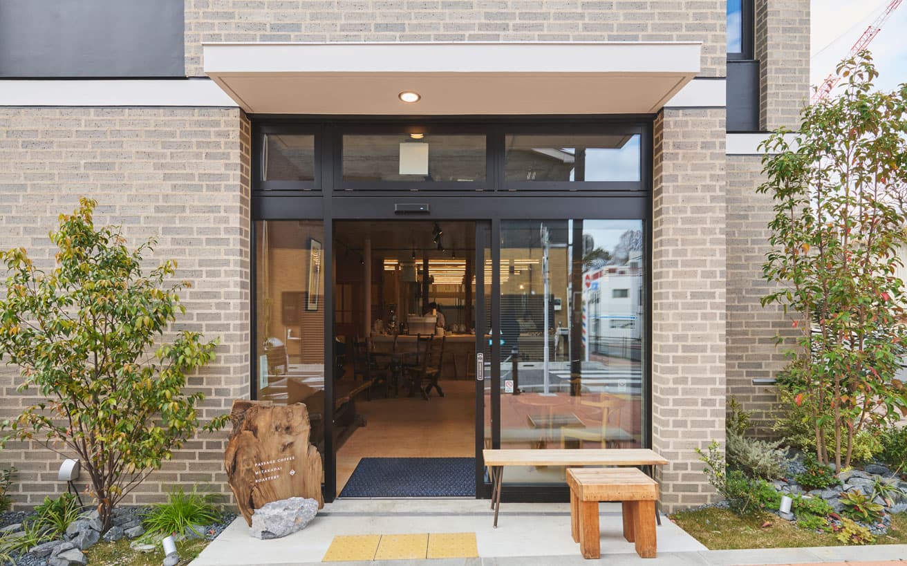 〈PASSAGE COFFEE MITAKADAI ROASTERY〉外観。ガラス張りとなっており、店内の様子を見通すことができる。古材を用いた看板も魅力的。