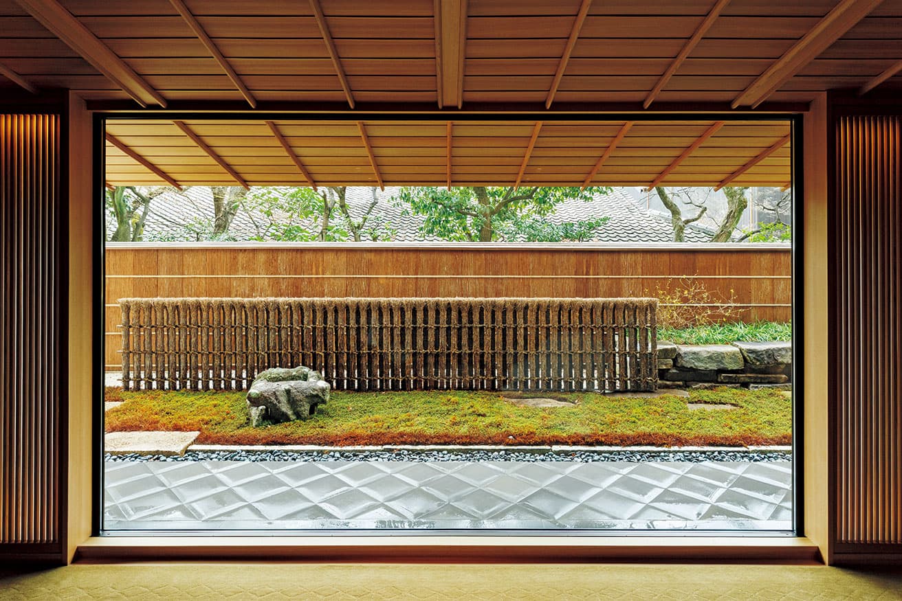 傾斜のある掛け込み天井がガラス窓の外の庇へと繋がり、低い視線を庭へと誘導する。奈良の茶人・河瀬虎三郎の庭にあった井戸枠、松明垣、杉皮塀、丹波石などで構成された庭。四季折々の風情ある景色が楽しめる。